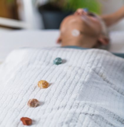 Healing and Balancing Chakras Therapy. Beautiful elderly woman lying on massage table and enjoying chakra healing treatment